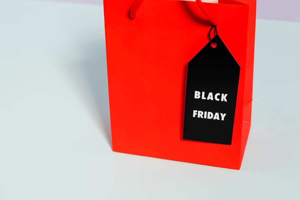 Sacola de compras vermelha com etiqueta preta escrita Black Friday sobre superfície clara
