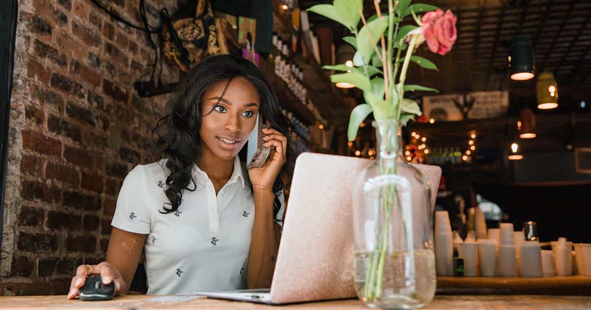 Empreendedora ao telefone com o notebook aberto, cuidando de duas frentes do negócio ao mesmo tempo