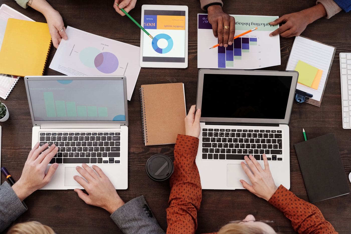 Equipe analisando gráficos de marketing em notebooks e papéis sobre uma mesa