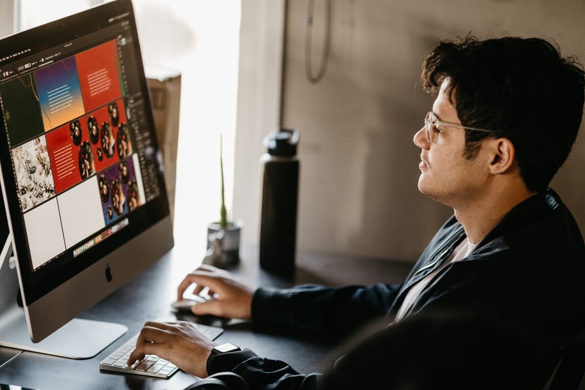 Designer de perfil olhando um monitor com várias artes coloridas em edição